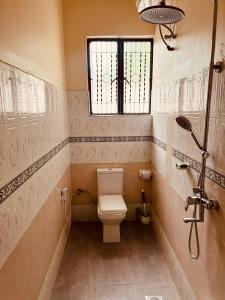 a bathroom with a toilet and a window at Makali Private Villa- 2En-Suite Bedrooms in Arusha +8 photos