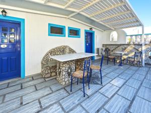 a patio with blue doors and tables and chairs at Stavros Beachfront Domes by Booking Kottas in Perivolos