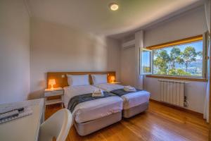 a bedroom with a large bed and a window at Central Suítes Arouca in Arouca +55 photos