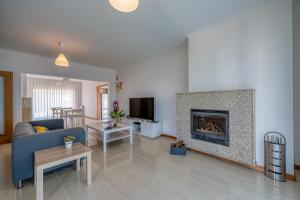 a living room with a blue couch and a fireplace at Central Suítes Arouca in Arouca