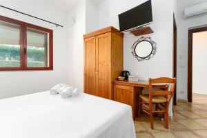 a bedroom with a bed and a desk and a tv at Sa Murta Bianca Guesthouse Budoni in Budoni