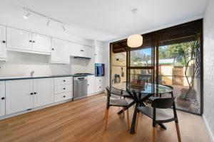 a kitchen with white cabinets and a glass table at Central Freo Hideaway in Fremantle