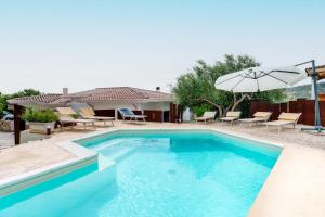 a swimming pool with chairs and an umbrella at Sa Murta Bianca Guesthouse Budoni in Budoni
