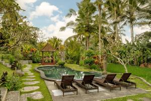 a resort pool with chairs and a gazebo at KERAMAN SUITE UBUD in Ubud