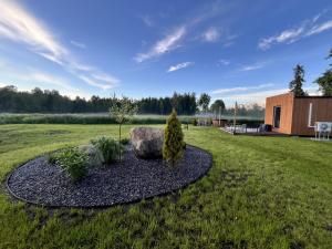 a garden with a rock and trees in a field at Napu Puhkemaja in Rabivere
