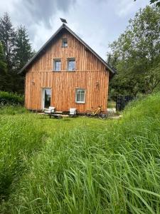 a large wooden barn with a bench in a field at Mlýnská 53 in Kraslice