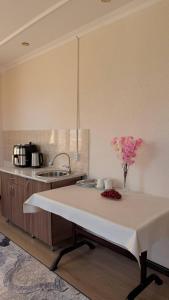 a kitchen with a table with a vase of flowers on it at Гостевой дом "Greenway Tourist" in Bosteri