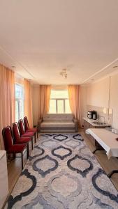 a living room with a large rug and red chairs at Гостевой дом "Greenway Tourist" in Bosteri