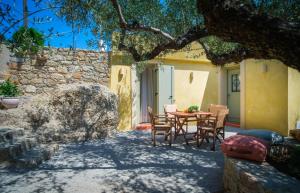 a patio with a table and chairs under a tree at Limni house in Kythira