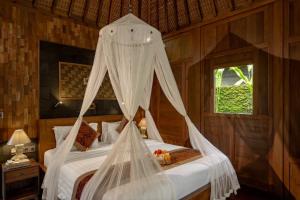 a bedroom with a bed with a mosquito net at KERAMAN SUITE UBUD in Ubud +56 photos