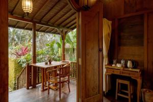 a room with a table and a fireplace on a porch at KERAMAN SUITE UBUD in Ubud