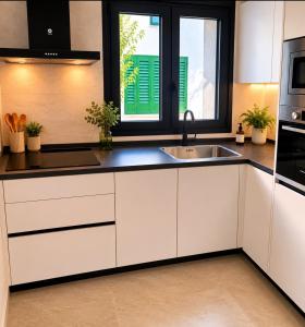 a kitchen with white cabinets and a sink at La casa Suiza in Cercedilla