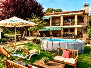 a backyard with a pool with chairs and an umbrella at Villa Sanz in Cuenca