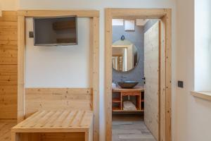 a bathroom with a tv on a wall next to a sink at Agritur Fiordaliso in Predaia