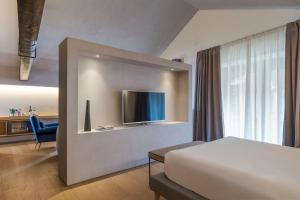 a bedroom with a bed and a tv on a wall at Habitat Boutique Hotel in Catania