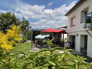 a patio with a red umbrella in a yard at Gîte EMOZIONE in Guebwiller