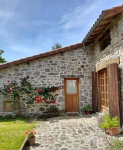 a stone house with a wooden door and flowers at Le Pre Vert - Garden Suite in Marat