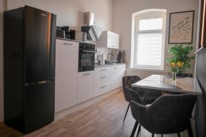 a kitchen with a black refrigerator and a table with chairs at FeWo LUNA in Riesa +11 photos