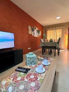a living room with a table and a television and a piano at Departamento duplex Champaqui in Villa General Belgrano