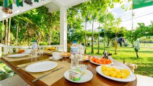 a wooden table with plates of fruit and water bottles at lake Edge Dambulla in Dambulla