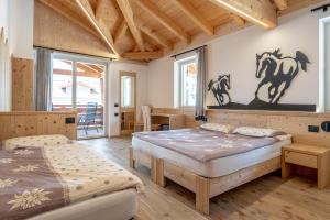 two beds in a room with wooden floors and windows at Agritur Fiordaliso in Predaia