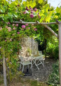 a table and chairs in a garden with flowers at Le Pre Vert - Garden Suite in Marat