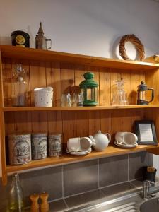 a kitchen shelf with dishes and other items on it at Le Pre Vert - Garden Suite in Marat