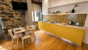a kitchen with yellow cabinets and a table at Heritage Apartments in Câmara de Lobos
