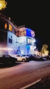 a white building with cars parked in front of it at Hotel Aqua Waterfall in Dharamshala