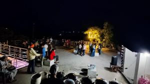 a crowd of people standing on a stage at night at Hotel Aqua Waterfall in Dharamshala