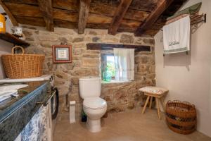 a bathroom with a toilet and a stone wall at Vivienda pasiega LO LUCAS 1920 in San Roque de Ríomiera +54 photos