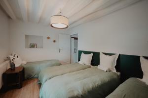 a bedroom with three beds with green sheets at Le gîte de Bresteau in Beillé +8 photos