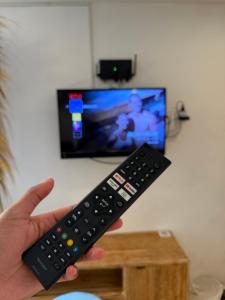 a person holding a remote control in front of a tv at Braban Sari Guest House Seminyak in Seminyak