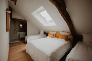 two beds in a attic room with a skylight at L'annexe de Bresteau in Beillé