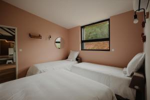 two beds in a room with a window at L'annexe de Bresteau in Beillé +3 photos
