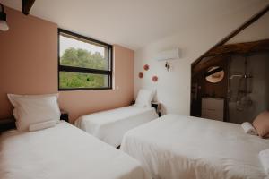 two beds in a room with a window at L'annexe de Bresteau in Beillé