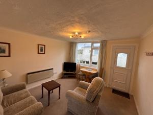 a living room with chairs and a television and a table at 1 Bedroom Chalet in West Runton