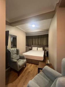 a bedroom with a bed and a couch and a chair at ERSA Hotel in Tuzla