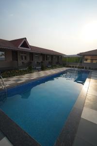 a large swimming pool with blue water in front of a building at khopoli resort in Khopoli +11 photos