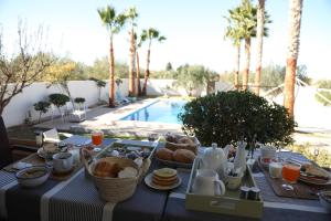 a table with breakfast food on it next to a pool at Dar Elferdaous in Al Medou