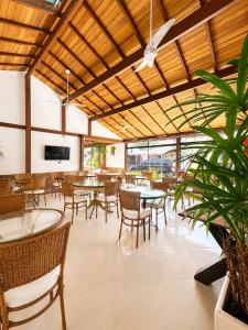 a dining room with tables and chairs and a television at Pousada Praia e Conforto in Búzios