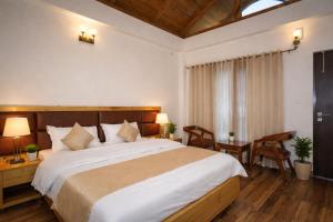 a bedroom with a large bed and a table and chairs at Aesquire Hotel in Bhīm Tāl