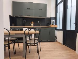 a kitchen with black cabinets and a table and chairs at Le Cleyputz in Dunkerque