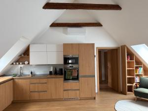 an attic kitchen with wooden cabinets and appliances at Apartmány u čalouníků in Litomyšl
