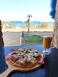 a pizza sitting on a table next to a drink at blue Bird in Nuweiba‘ el Muzeinah +139 photos