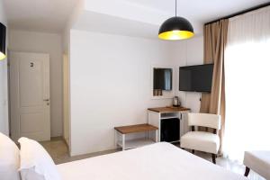 a bedroom with a bed and a desk and a tv at Amber Butik Otel in Çeşme