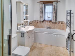 a bathroom with a tub and a sink and a toilet at Jacks Barn - Hssu in Welcombe