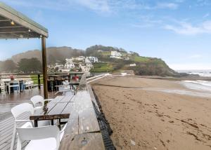 a table and chairs on a beach with the ocean at Millendreath Beach Resort in Looe