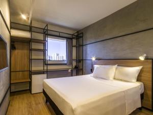 a bedroom with a large white bed and a window at ibis Ribeirao Preto Vila do Golf Shopping in Ribeirão Preto