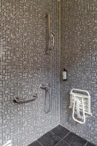 a bathroom with a shower with a stool in it at The Originals Access, Halt'Hotel, Clermont Agnetz in Agnetz +31 photos